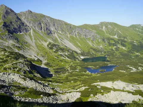 Blue alpine lakes surrounded by green and rocky mountain ridges
